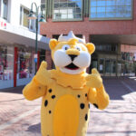 Ein Mensch als Leo der Leopard verkleidet, das Stadtmaskottchen von Georgsmarienhütte, hält beide Daumen hoch.